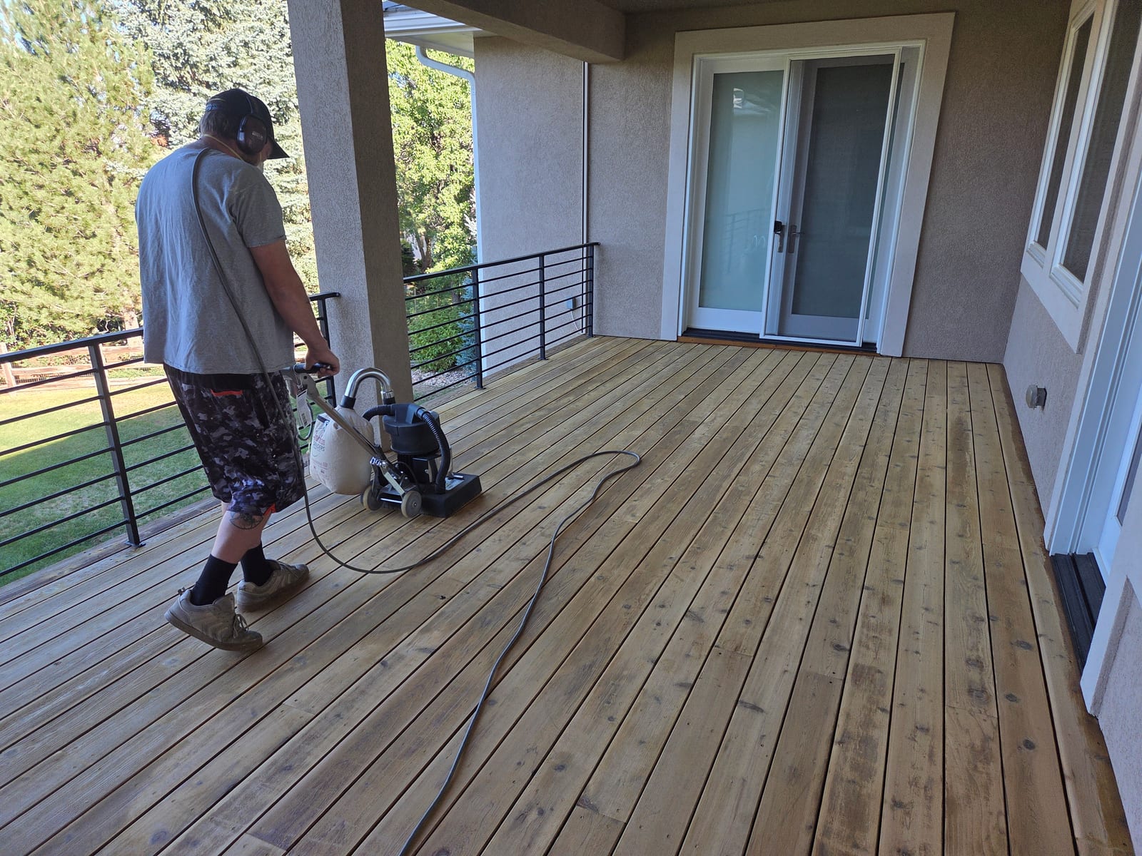 Technician sanding a bare wood deck before staining