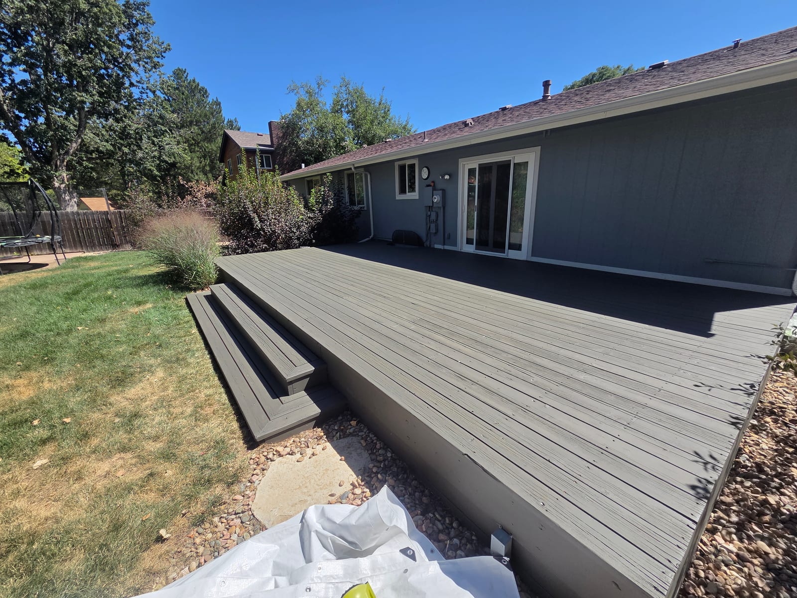 Backyard wood deck finished in a solid gray stain with built-in steps