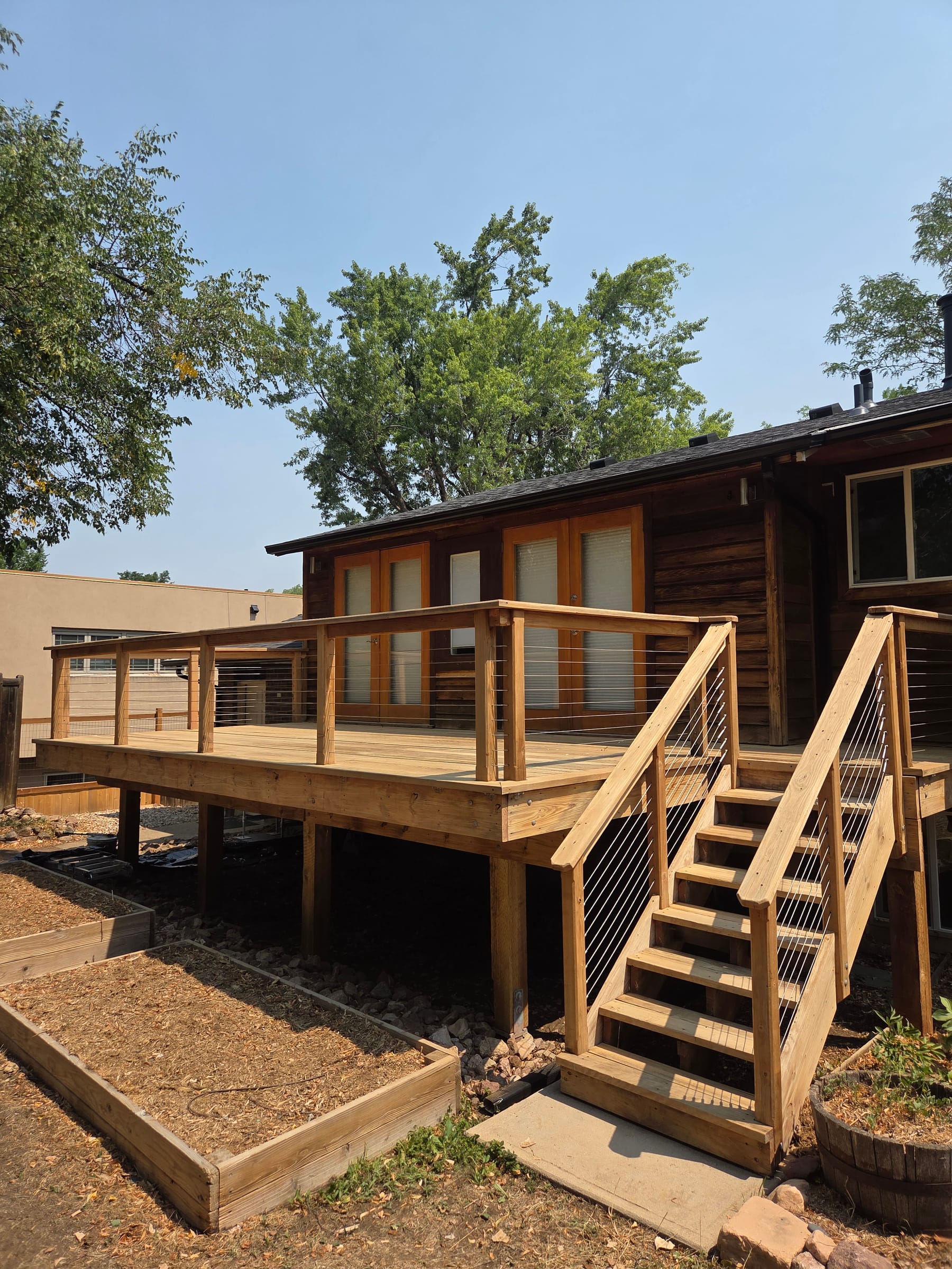 Newly built wood deck and staircase with cable railing, stained to match the home